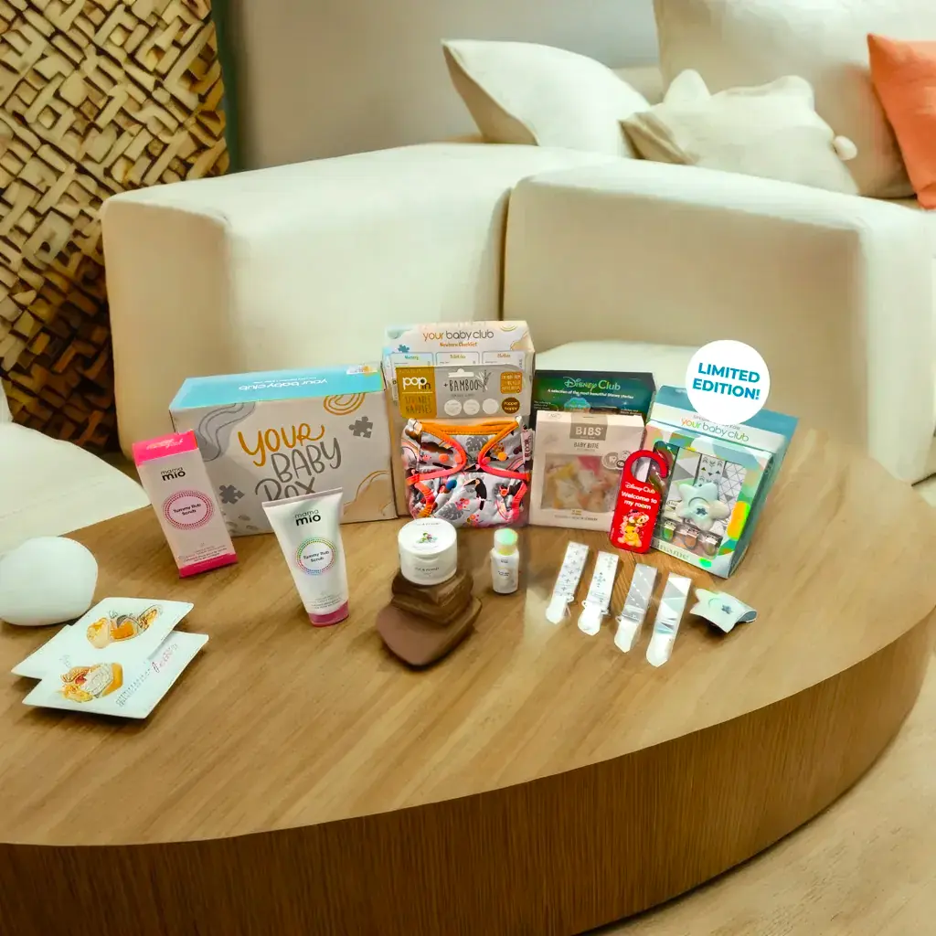 boxes with baby freebies on a wooden table in front of a livingroom sofa