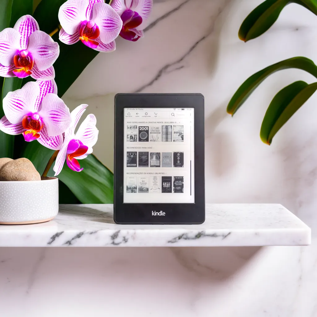 a kindle tablet on a marble shelf next to very light pink orchids